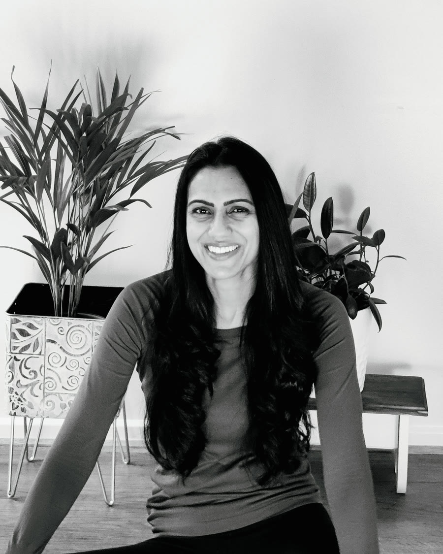 Deepti Nair, smiling, seated in front of plants